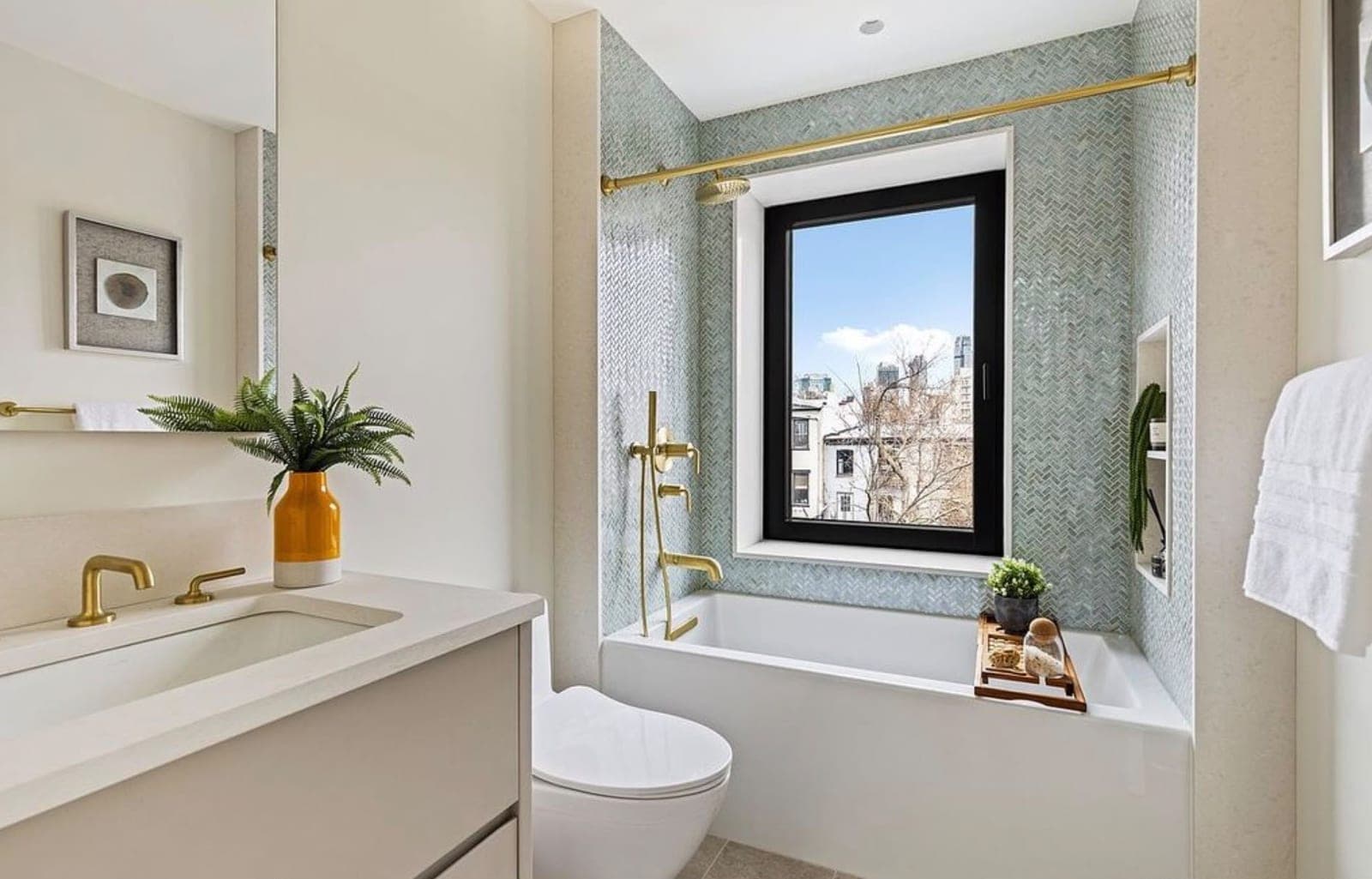 Finished bathroom with a wall-hung vanity, brass fixtures and a tub under the window