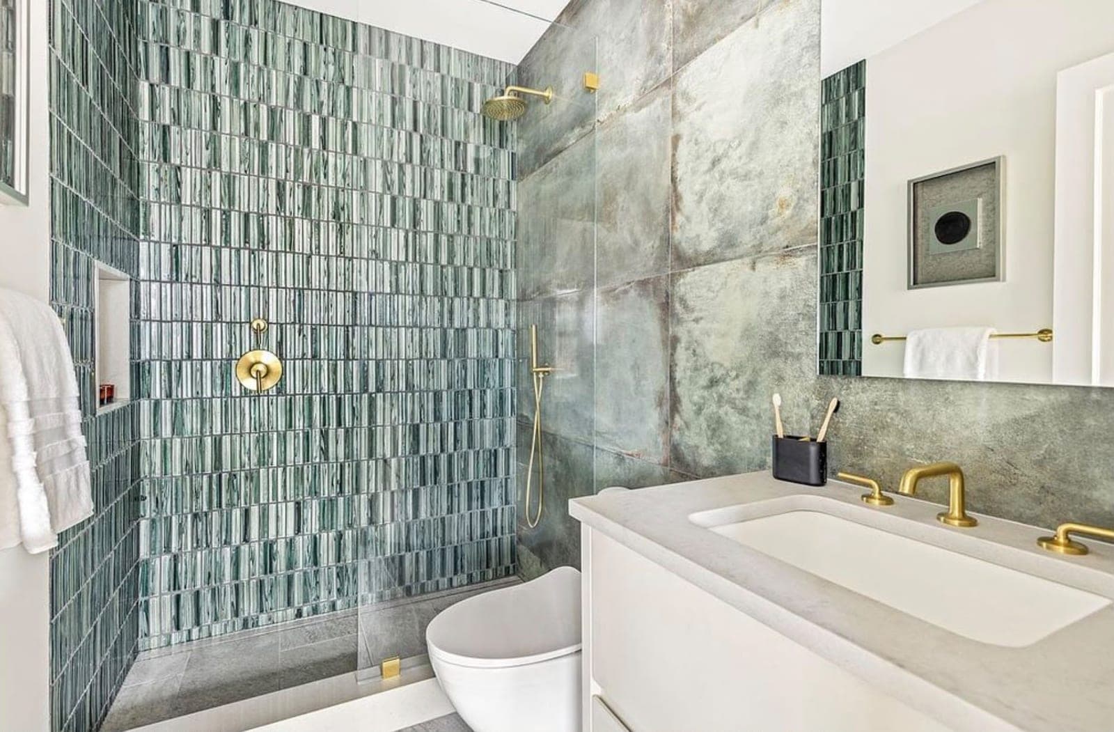Finished bathroom with a green tiled glass shower and brass fixtures